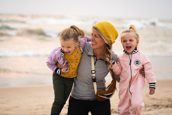 Lachende Mutter mit zwei Kindern am Strand